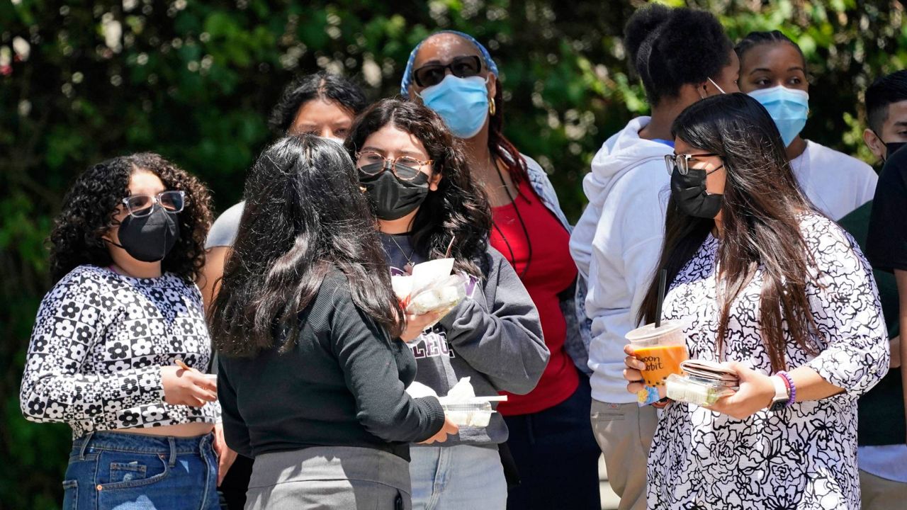 People wear face masks while waiting at a bus stop in Los Angeles in July. (AP Photo, File)