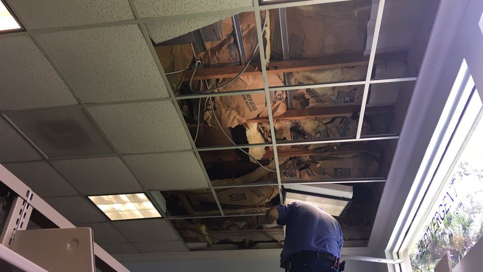 Crews busy working inside and outside the Main Brooksville library to repair damage done over the weekend by a suspected break-in through the library's roof, Monday, July 30, 2018. 