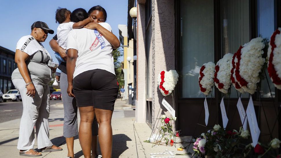 Family members of slain mass shooting victim Thomas "TJ" McNichols, from left, Donna Johnson, aunt, and sisters Jamila and Finesse McNichols, mourn beside a memorial near the scene of the shooting Monday, Aug. 5, 2019, in Dayton, Ohio. (AP Photo/John Minchillo)