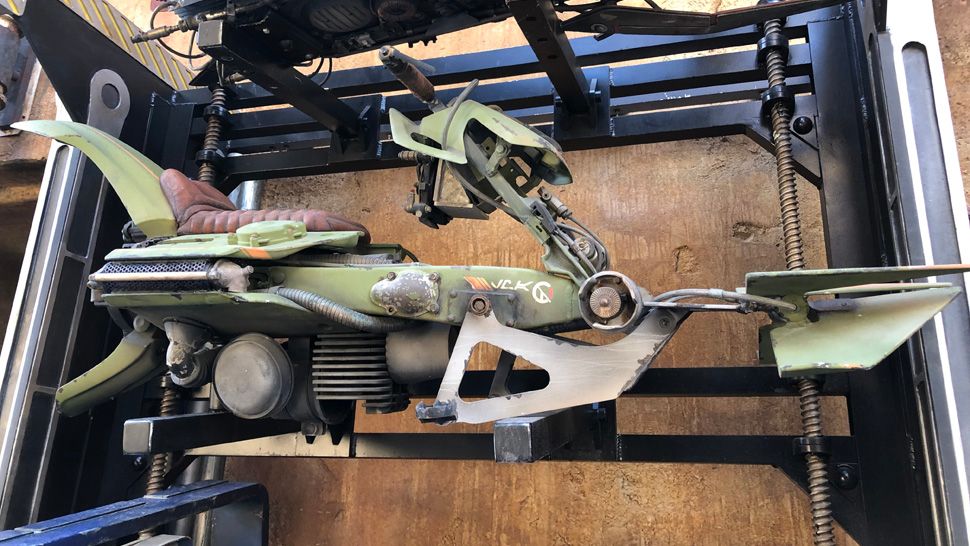 In Black Spire Outpost Marketplace, this green speeder bike has the letters :LMA" painted on it in Aurebesh. What could they mean? (Ashley Carter/Spectrum News 13)