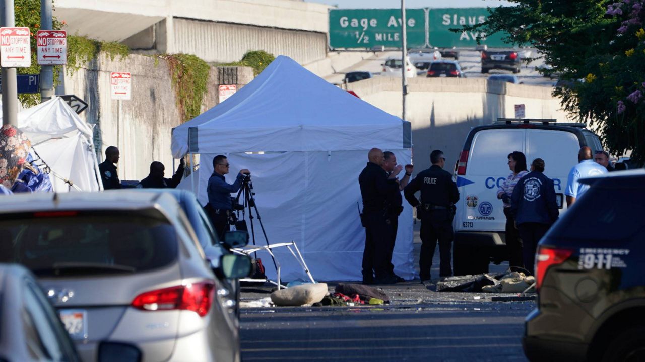 Police investigators and members of the Los Angeles County Department of Medical Examiner-Coroner set up a tent before removing the bodies of two people killed on Tuesday. (AP Photo/Damian Dovarganes)