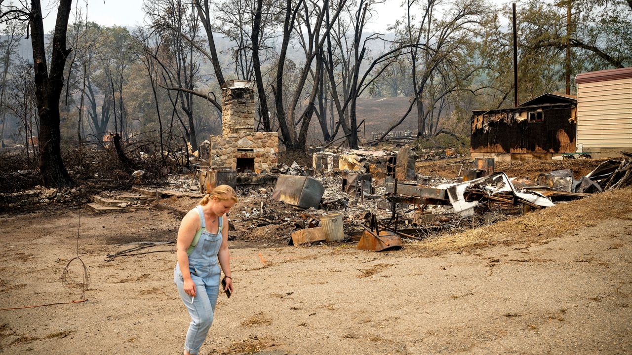 Sydney Corrales passes a lodge that burned during the McKinney Fire, Tuesday, Aug. 2, 2022, in Klamath National Forest, Calif. (AP Photo/Noah Berger)