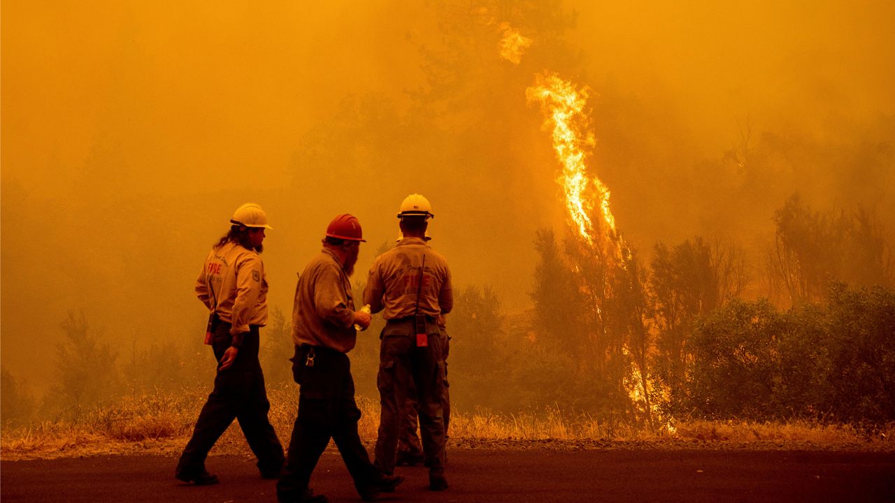 Flames from the McKinney Fire burn beyond firefighters in Klamath National Forest, Calif., on Sunday, July 31, 2022. (AP Photo/Noah Berger)