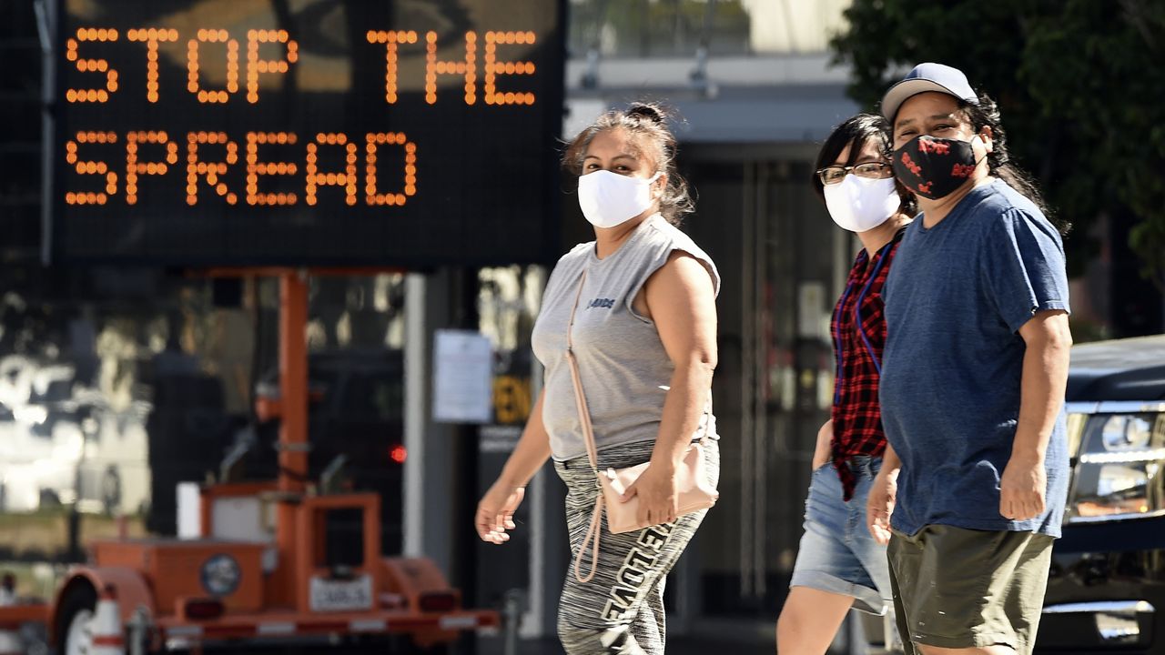 Pedestrians wear masks as they walk in front of a sign reminding the public to take steps to stop the spread of coronavirus in Glendale, Calif. Barbara Ferrer, L.A. county director of the Department of Public Health, said infection rates among residents aged 30 to 49 nearly tripled between June and late July, and rates among those 18-29 quadrupled. (AP Photo/Chris Pizzello, File) 