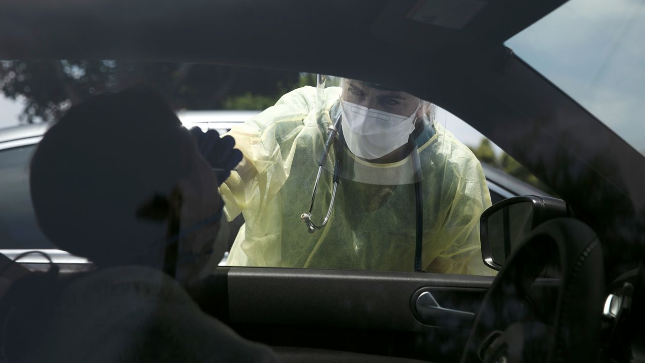 In this June 25, 2020, file photo, physician assistant Nicole Kramer collects a nasal swab sample from a patient for COVID-19 testing in Tustin, Calif., in Orange County. The Orange County Health Care Agency Wednesday reported a dozen COVID-19 fatalities, raising the coronavirus death toll to 665.