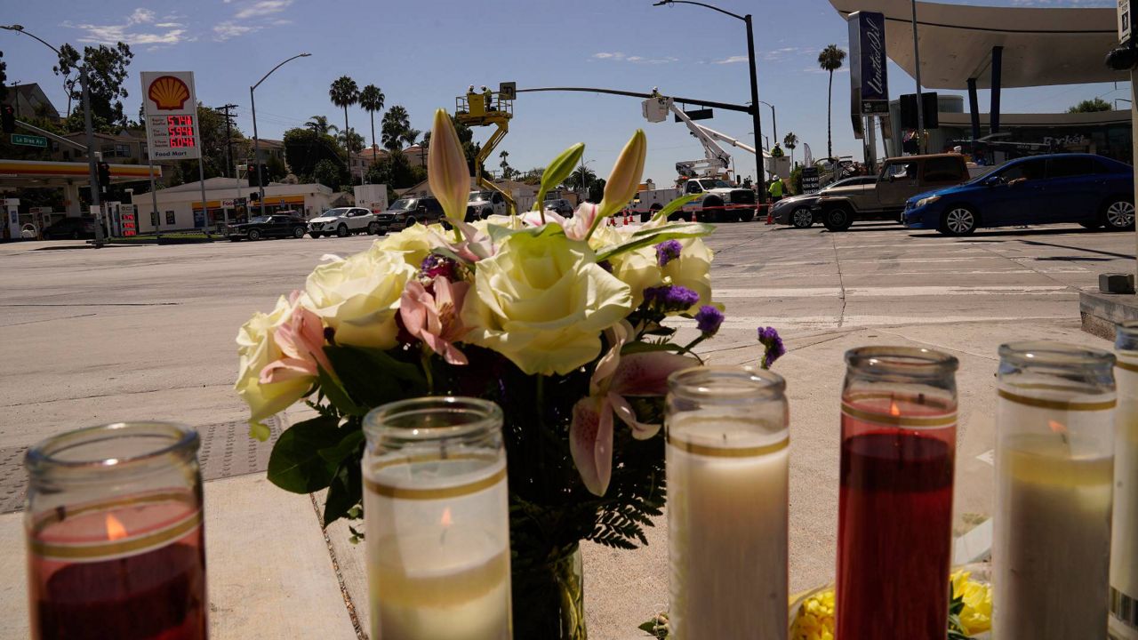 Neighbor Mary Thompson prays as she brings a bouquet to the memorial site set after a crash involving as many as six cars near a gas station in the unincorporated Windsor Hills in Los Angeles on Friday. (AP Photo/Damian Dovarganes)