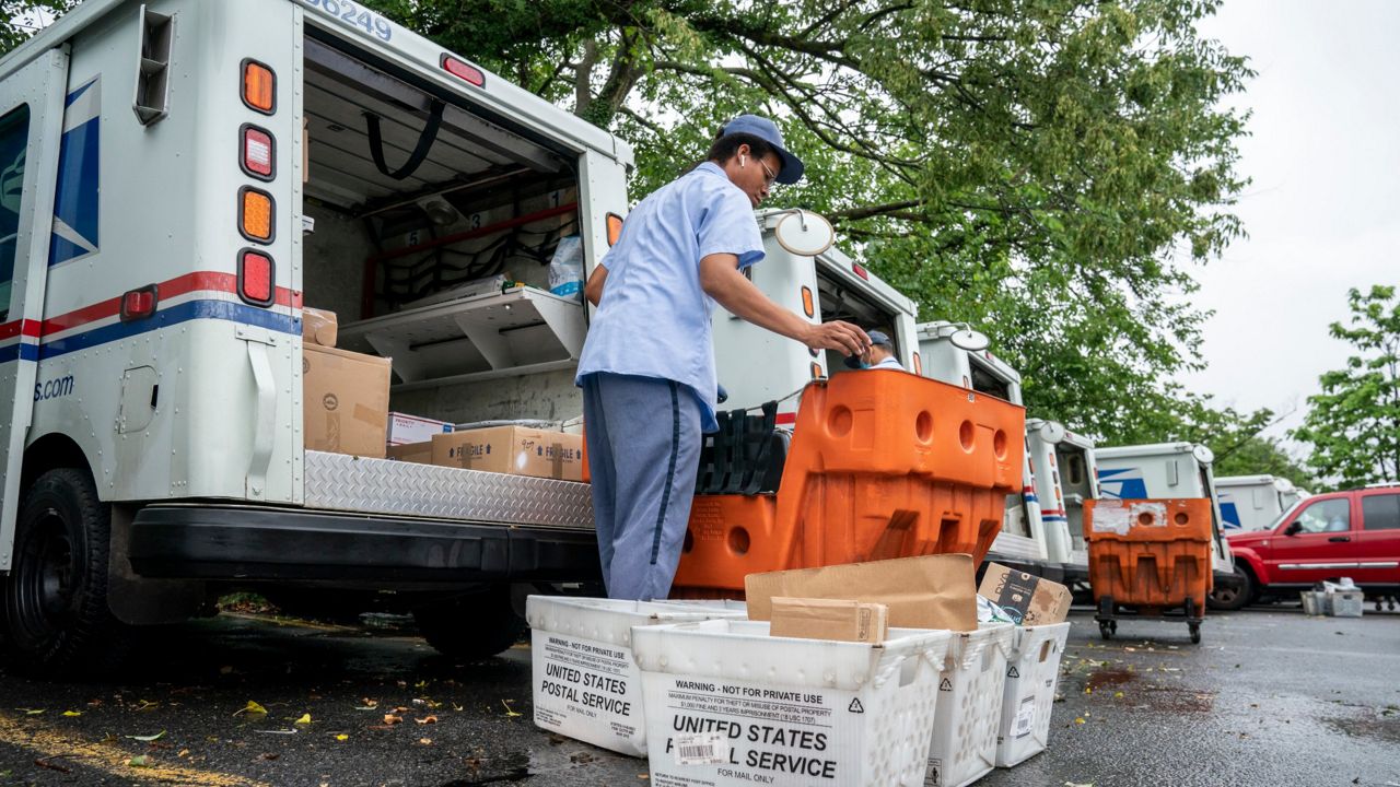 Letter carriers load mail trucks for deliveries at a U.S. Postal Service facility. (AP Photo)