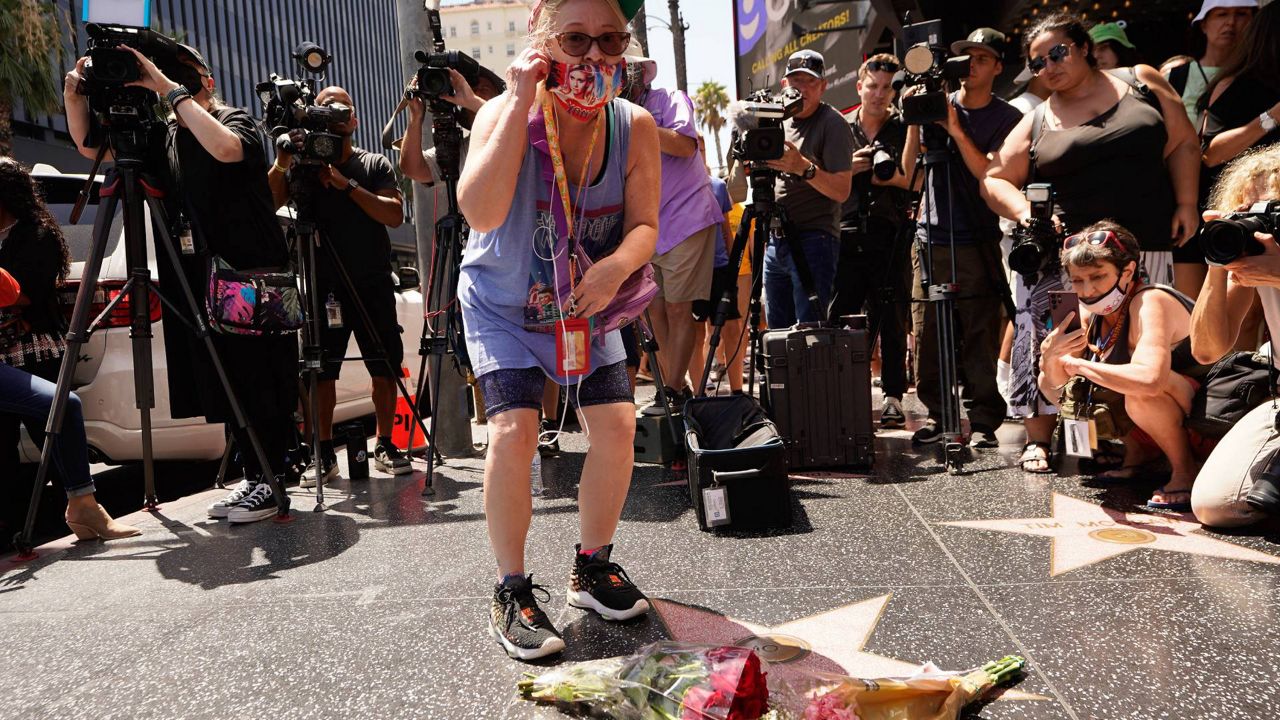 A fan honors actor Olivia Newton-John with flowers on Newton-John's Hollywood Walk of Fame star in Los Angeles on Monday. (AP Photo/Damian Dovarganes)