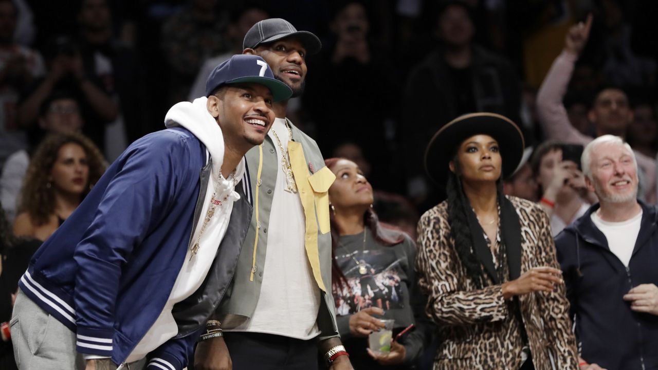 Carmelo Anthony, left, LeBron James, second from left, and Gabrielle Union, second from right, watch as Miami Heat guard Dwyane Wade plays his final NBA basketball game, against the Brooklyn Nets on Wednesday, April 10, 2019, in New York. (AP Photo/Kathy Willens)