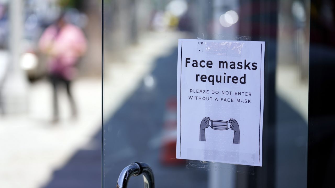 A sign advises shoppers to wear masks outside of a story Monday, July 19, 2021, in the Fairfax district of Los Angeles. (AP Photo/Marcio Jose Sanchez)