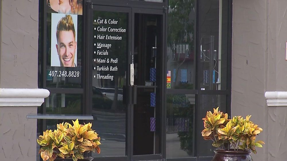 The glass on a door was broken at a salon at a shopping plaza on Sand Lake Road in Orlando overnight. (Spectrum News)