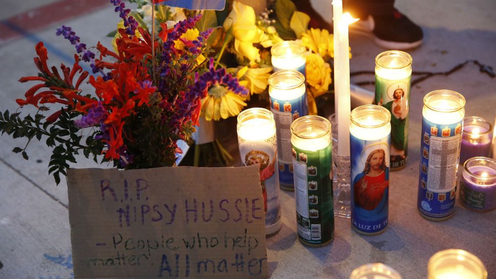 A sign for rapper Nipsey Hussle is left by candles set up across from a clothing store owned by Hussle in Los Angeles, Sunday, March 31, 2019. Hussle, the skilled and respected West Coast rapper who had a decade-long success with mixtapes but hit new heights with his Grammy-nominated major-label debut album in 2018, has died. He was 33. (AP Photo/Damian Dovarganes)