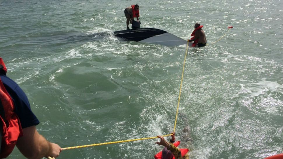 This Monday, Aug. 13, 2018, photo provided by the U.S. Coast Guard shows three boaters being rescued from their capsized 24-foot vessel near Galveston, Texas. All three men were unharmed. (Edward Wargo/U.S. Coast Guard via AP)