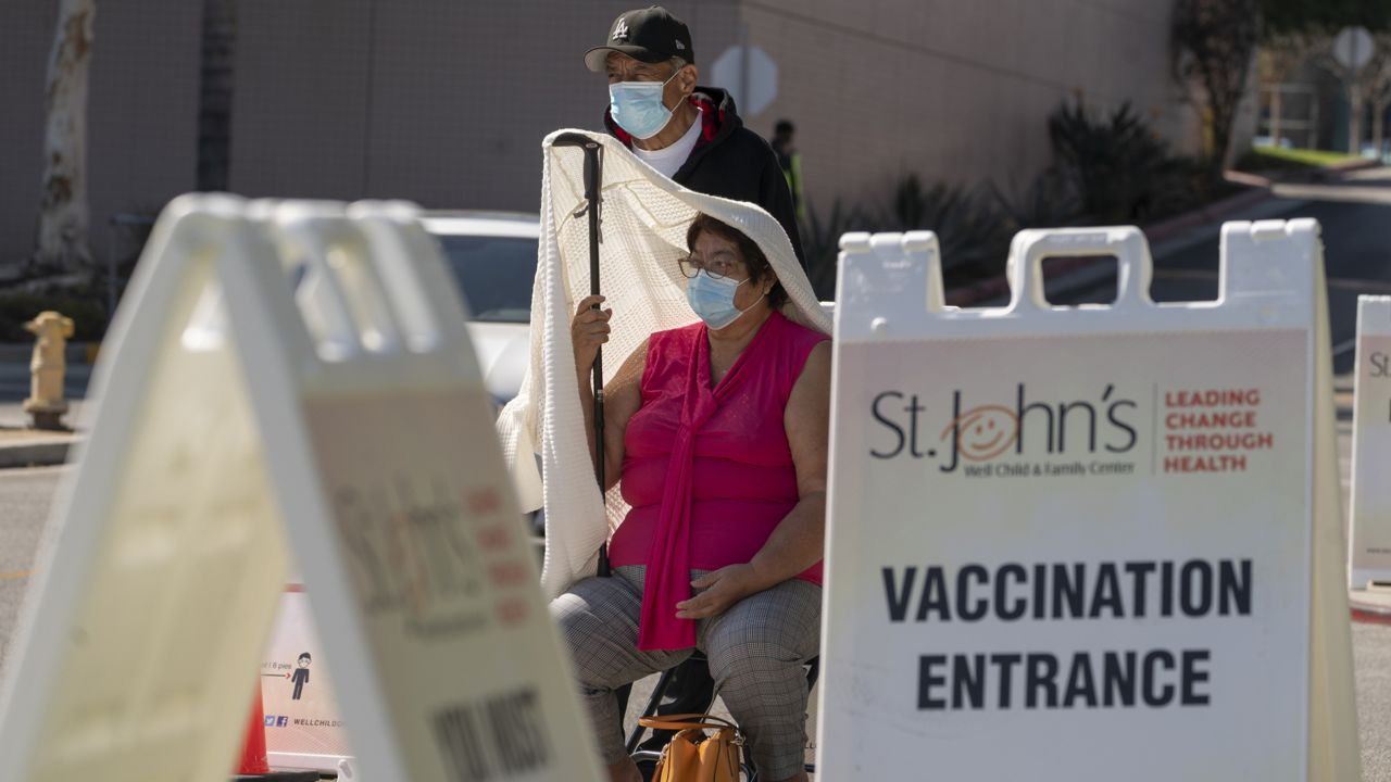 Jose Rosas and his wife, Sara, who live in the 90060 zip code, wait in line to be screened for high temperature before being vaccinated at the St. John's Well Child and Family Center at the East Los Angeles Civic Center in Los Angeles, Thursday, March 4, 2021. (AP Photo/Damian Dovarganes)