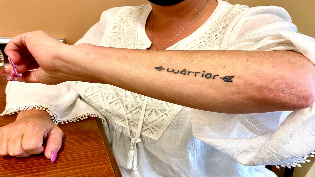 A tattoo on a woman's arm that says warrior.