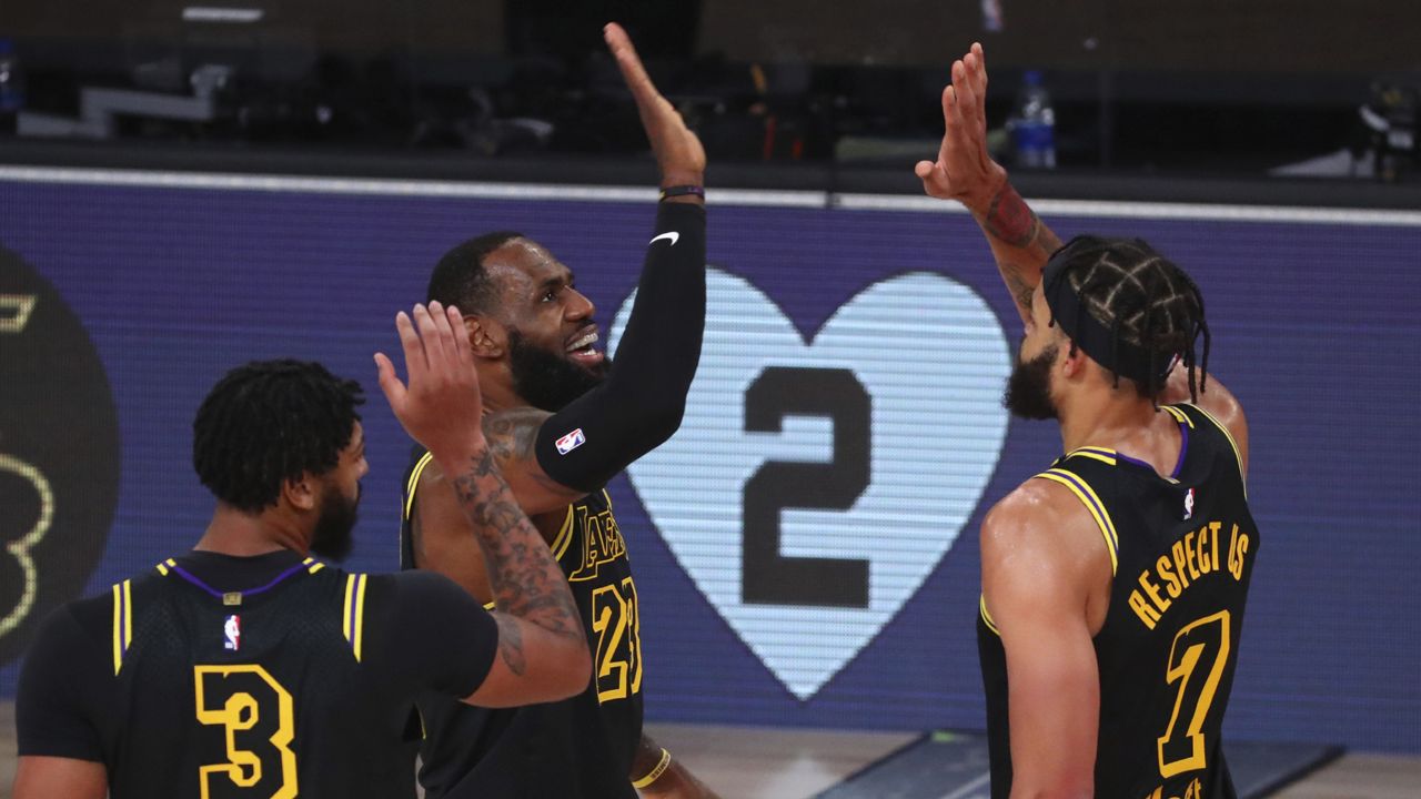 Los Angeles Lakers forward LeBron James (23) celebrates after scoring a three-point basket with center JaVale McGee (7) and forward Anthony Davis (3) in the first half of Game 4 of an NBA basketball first-round playoff series against the Portland Trail Blazers, Monday, Aug. 24, 2020, in Lake Buena Vista, Fla. (Kim Klement/Pool Photo via AP)