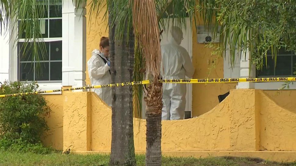 Sheriff's investigators in protective suits work at a home where a woman's body was found Friday. Two toddlers spotted wandering led a passerby to the home, where the woman's body was found. (Vincent Earley, staff)