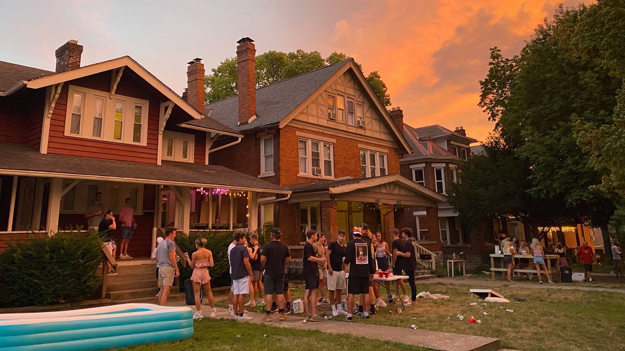 A group of college students party in front of a house