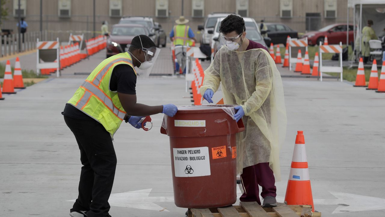 In this July 22, 2020 file photo, workers collect samples at a mobile coronavirus testing site in Los Angeles. (AP Photo/Marcio Jose Sanchez, File)