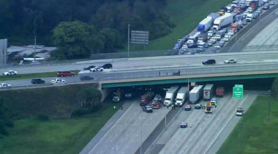 Semi trucks block both east- and westbound Florida's Turnpike under the Kirkman Road overpass Tuesday afternoon while authorities talk to a person who climbed over the overpass fence. (Sky 13)