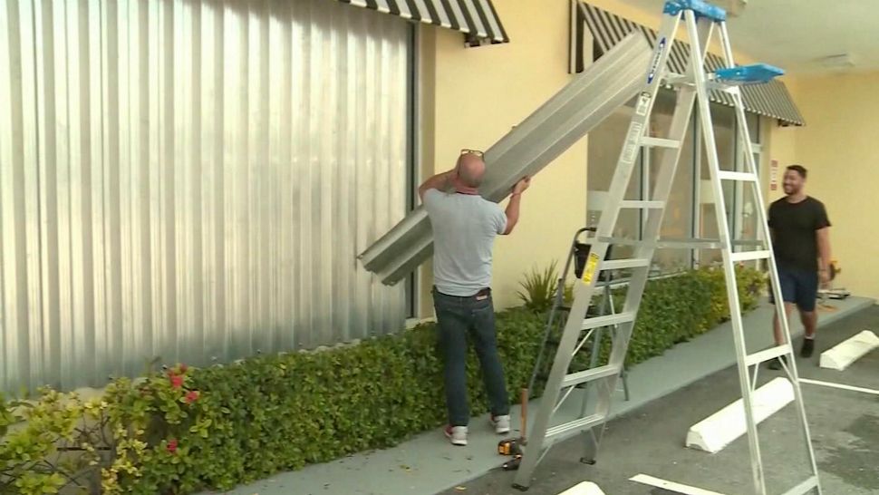 A man boards up his business ahead of a landfalling tropical system. (Spectrum News)