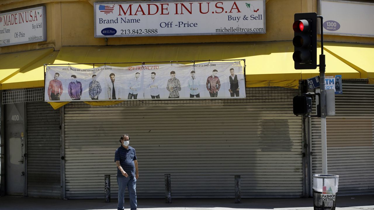 A man walks in front of a shuttered store Monday, May 4, 2020, in the fashion district of Los Angeles. (Marcio Jose Sanchez/AP)