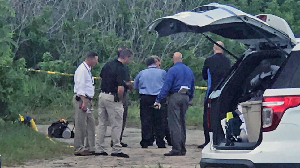 Law enforcement officers conduct an investigation near the Pineda Causeway on Wednesday afternoon after a fisherman found a body in the Banana River. (Greg Pallone, staff)