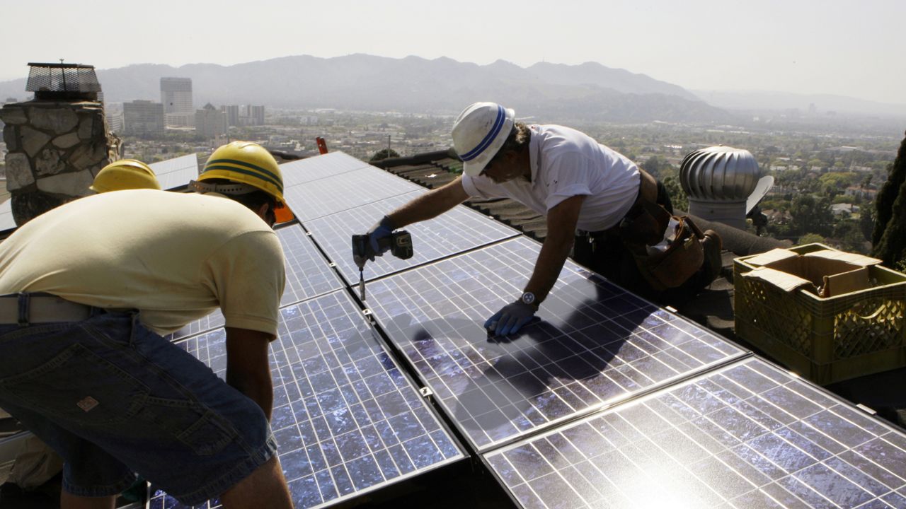 Workers from California Green Design install solar electrical panels on the roof of a home in Glendale, Calif. (AP Photo/Reed Saxon)