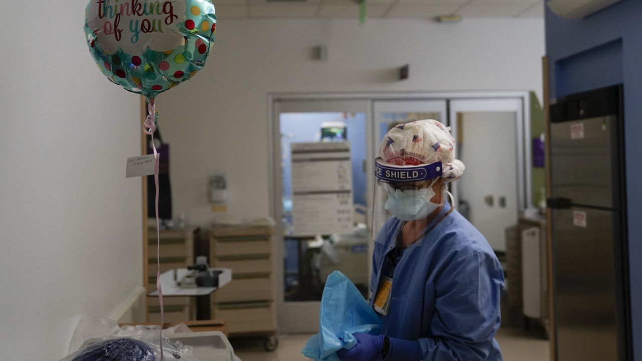 In this Jan. 7, 2021, file photo, registered nurse Anita Grohmann puts on her PPE next to a balloon delivered to a patient in a COVID-19 unit at St. Joseph Hospital in Orange, Calif. (AP Photo/Jae C. Hong)