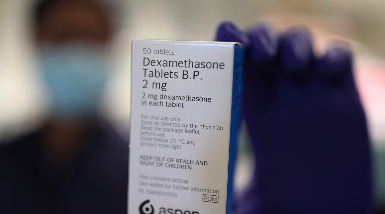 A member of staff at a pharmacy holds a packet of anti-inflammatory drug dexamethasone, in London, Thursday, June 18, 2020. (Yui Mok/PA via AP)