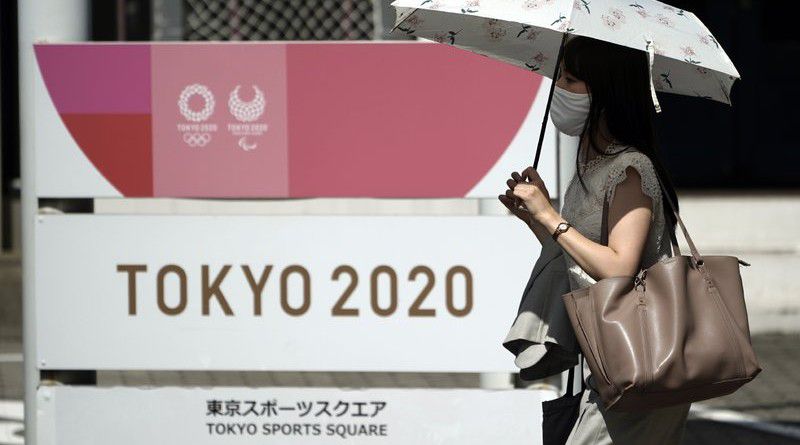 A woman wearing a face mask to help curb the spread of the coronavirus walks in front of Tokyo 2020 sign Friday, Sept. 4, 2020, in Tokyo. (AP Photo/Eugene Hoshiko)