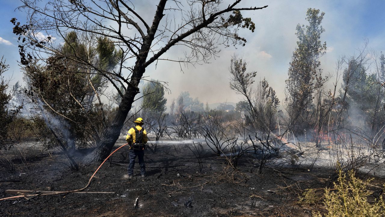 Los Angeles fire department firefighter works to douse the remains of a brush fire in the Sepulveda Basin in the Sherman Oaks area of Los Angeles on Sunday, Sept. 6, 2020.