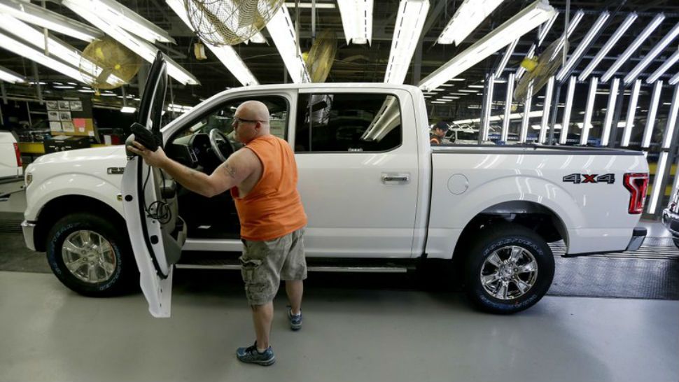 FILE- In this March 13, 2015, file photo, a worker inspects a new 2015 aluminum-alloy body Ford F-150 truck at the company’s Kansas City Assembly Plant in Claycomo, Mo. Under pressure from U.S. safety regulators, Ford is recalling about 2 million F-150 pickups in North America because the seat belts can cause fires. The recall covers certain trucks from the 2015 through 2018 model years. (AP Photo/Charlie Riedel, File)
