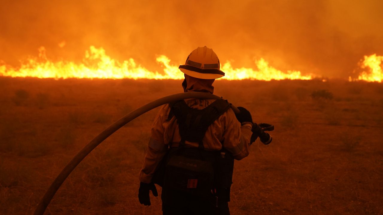 Alexis Miller of Los Angeles County Fire holds a water hose while protecting a home from the advancing Bobcat Fire along Cima Mesa Rd. Friday, Sept. 18, 2020, in Juniper Hills, Calif. (AP Photo/Marcio Jose Sanchez)