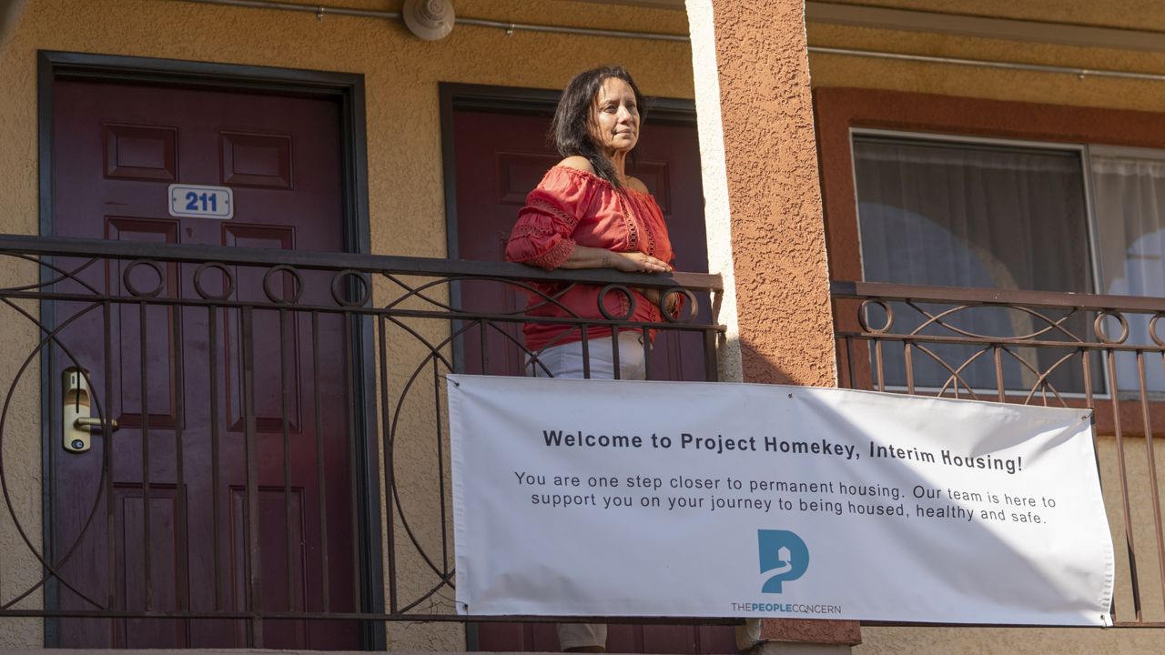 In this Wednesday, June 30, 2021, photo Veronica Perez poses outside her new home at the Mollie Mason Project Homekey site in Los Angeles. (AP Photo/Damian Dovarganes)