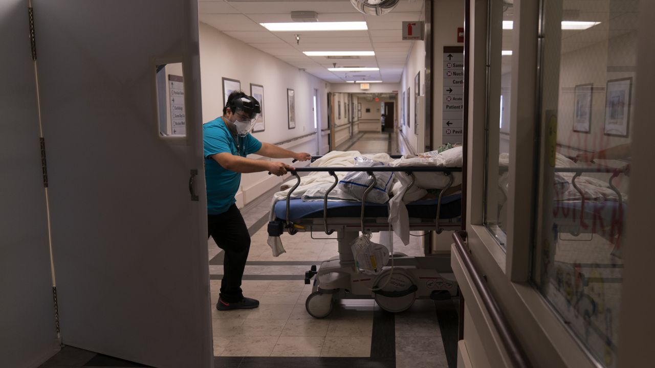 Medical transporter Adrian Parrilla moves a patient into a COVID-19 unit at Mission Hospital in Mission Viejo, Calif. on Feb. 19, 2021. (AP Photo/Jae C. Hong)