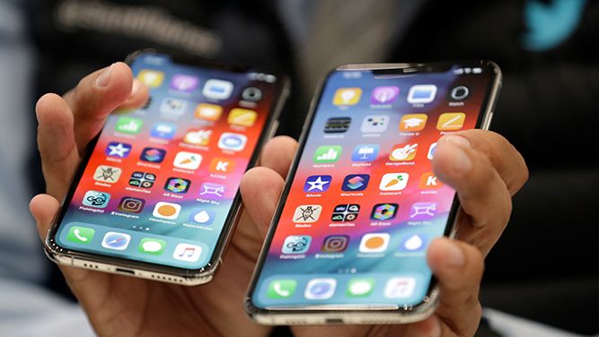 Person holding two new iPhones
