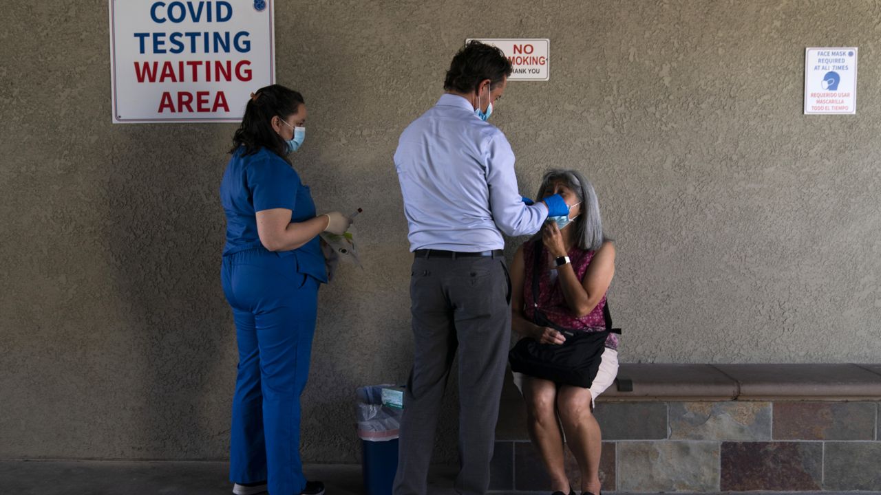 Dr. Neal Schwartz, center, collects a nasal swab sample from Debbie Lum for COVID-19 testing at Families Together of Orange County Thursday, Aug. 26, 2021, in Tustin, Calif. (AP Photo/Jae C. Hong)