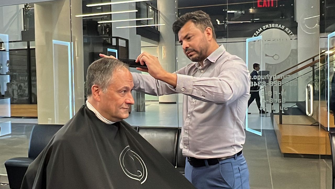 Second gentleman gets a haircut from barber Hugo Gonzalez at Cuts by Hugo in Washington, D.C., as part of a tour of Latino-owned small business. (Spectrum News/Cassie Semyon)