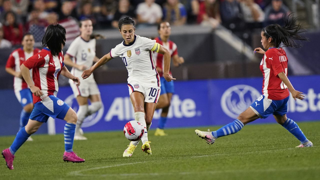 U.S. forward Carli Lloyd, center, moves the ball past Paraguay midfielders Fanny Godoy, left, and Cynthia Ayala, right, during the second half of an international friendly soccer match Thursday, Sept. 16, 2021, in Cleveland. USA won 9-0. (AP Photo/Tony Dejak)