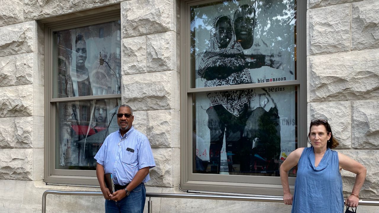 Project manager Barry Burton and artist Marjorie Guyon stand next to two ancestor portraits on translucent tapestries that are part of the "I Was Here" public art project in downtown Lexington.