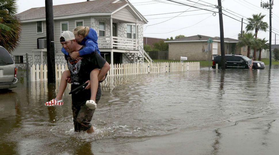 Terry Spencer carries his daughter, Trinity, through high water on 59th Street near Stewart Road in Galveston, Texas, Wednesday, September 18, 2019, as heavy rain from Tropical Depression Imelda caused street flooding on the island. (Jennifer Reynolds/The Galveston County Daily News via AP)