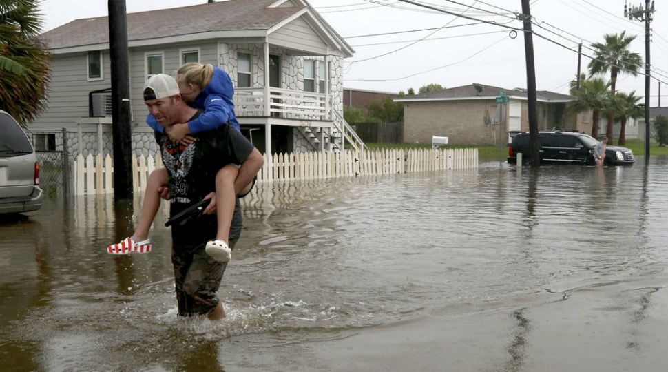 A man with a child on his back walks through the floodwaters of Imelda. (AP Images)