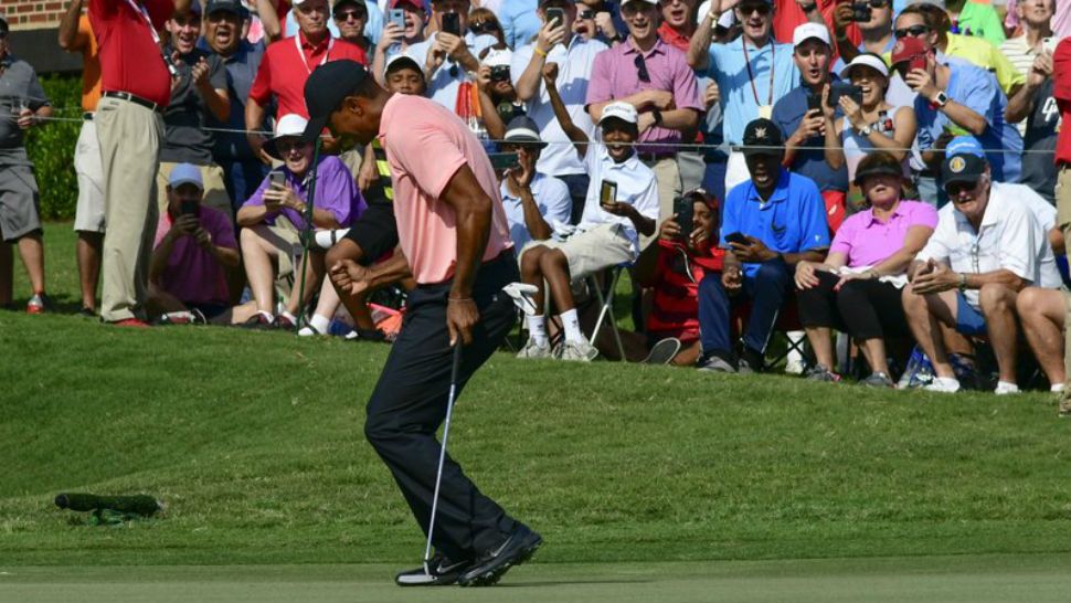 Tiger Woods reacts as he makes a eagle putt on the 18th green during the first round of the Tour Championship golf tournament Thursday, Sept. 20, 2018, in Atlanta. (AP Photo/John Amis)