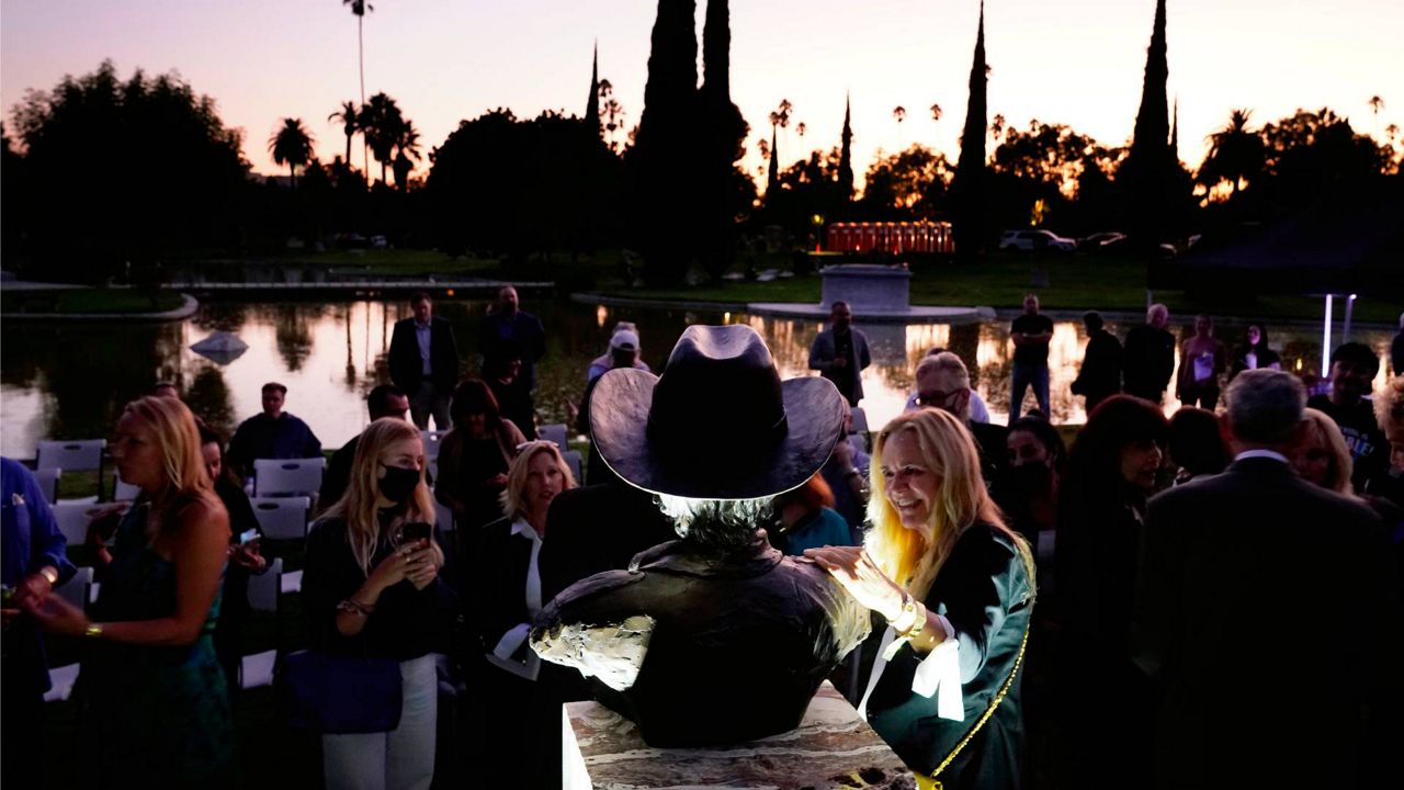 Guests gather around a newly unveiled memorial sculpture of the late actor Burt Reynolds following a ceremony at Hollywood Forever Cemetery, Sept. 20, 2021, in Los Angeles. (AP Photo/Chris Pizzello)