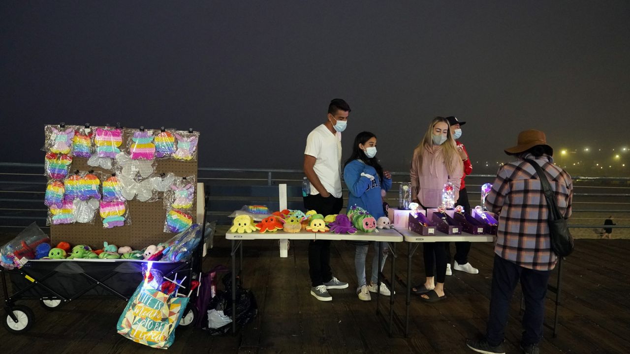 Visitors wear face masks as they buy items from a street vendor Wednesday, Sept. 8, 2021, in Santa Monica, Calif. (AP Photo/Marcio Jose Sanchez)