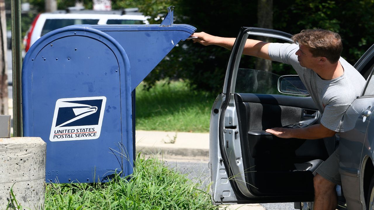 A person drops mail into a mailbox in Annapolis, Maryland, Tuesday, Aug. 18, 2020. (AP Photo/Susan Walsh)
