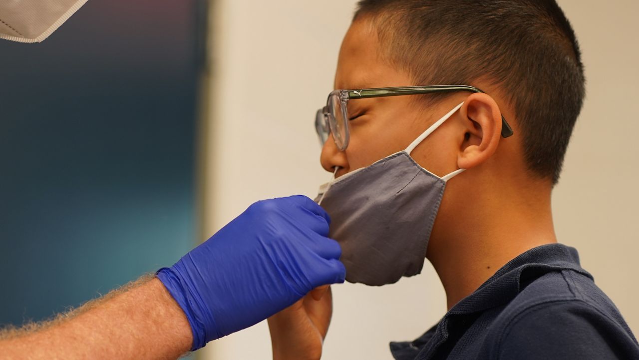 COVID test swab is administered to a young student.