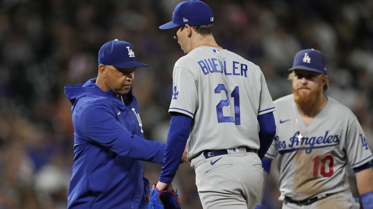 Los Angeles Dodgers manager Dave Roberts, left, takes the ball from starting pitcher Walker Buehler as he leaves the mound after giving up a two-run double to Colorado Rockies' German Marquez in the fourth inning of a baseball game Wednesday, Sept. 22, 2021, in Denver. (AP Photo/David Zalubowski) 