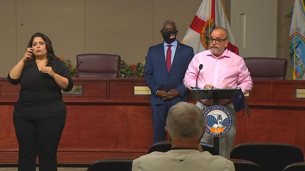 Orange County Health Officer Dr. Raul Pino as Orange County Mayor Jerry Demings looks on behind him during a news conference Friday afternoon following Gov. Ron DeSantis's announcement that the state would move to Phase 3 of its reopening plan. (Spectrum News 13)